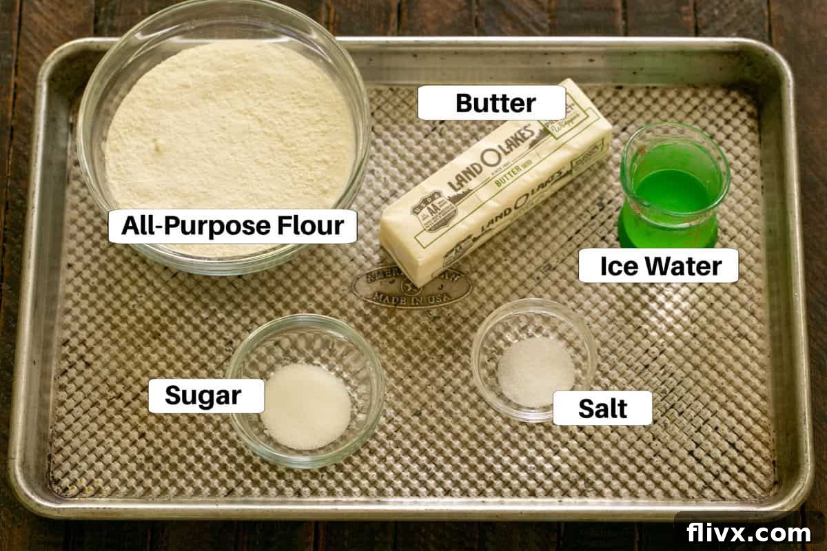Close-up view of peach galette crust ingredients laid out on a sheetpan with clear labels for each item: flour, butter, sugar, and salt, highlighting the fresh, quality components.