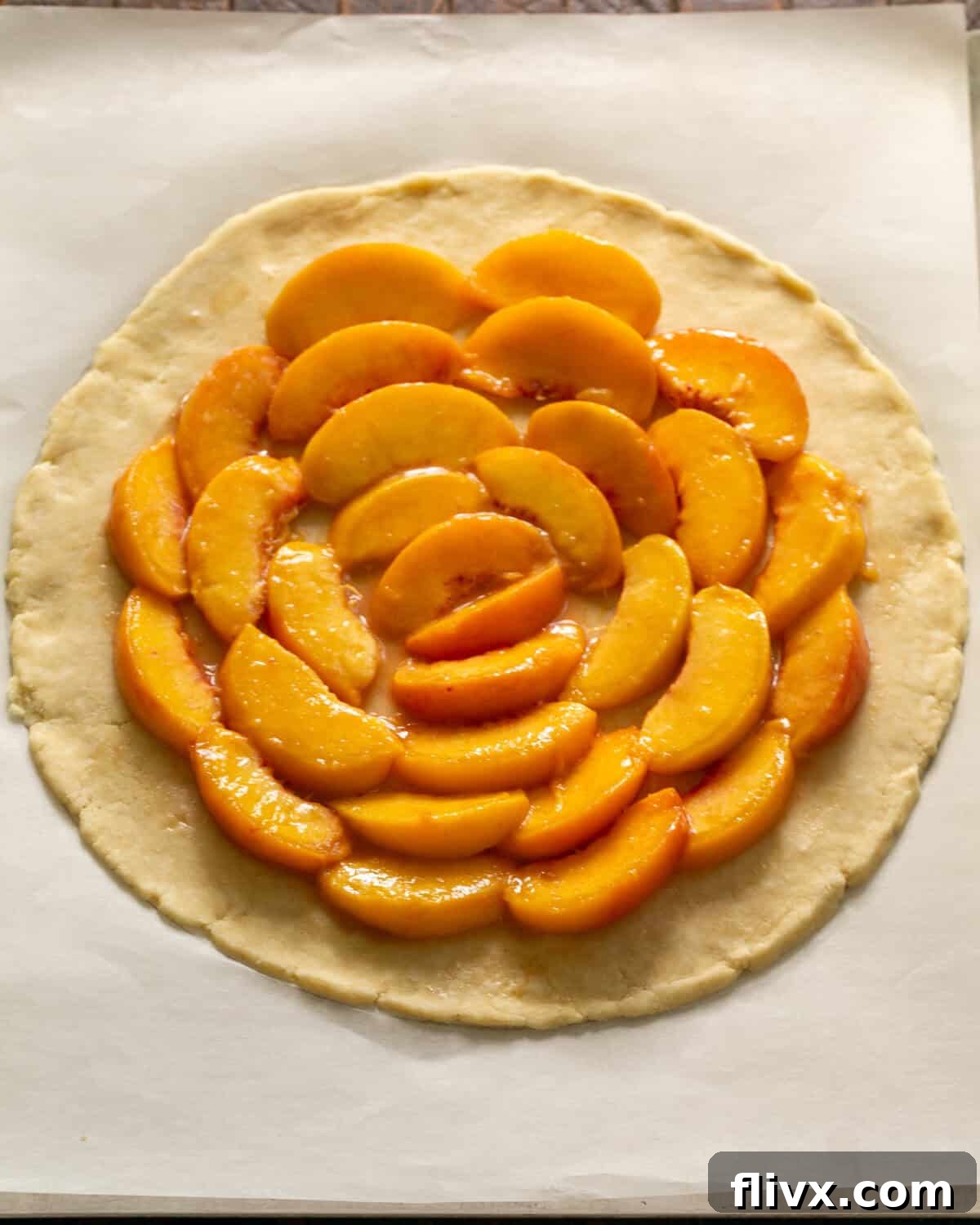 Step 5: Freshly sliced peaches are artfully arranged in concentric circles at the center of the rolled-out dough, leaving a clear border around the edge.