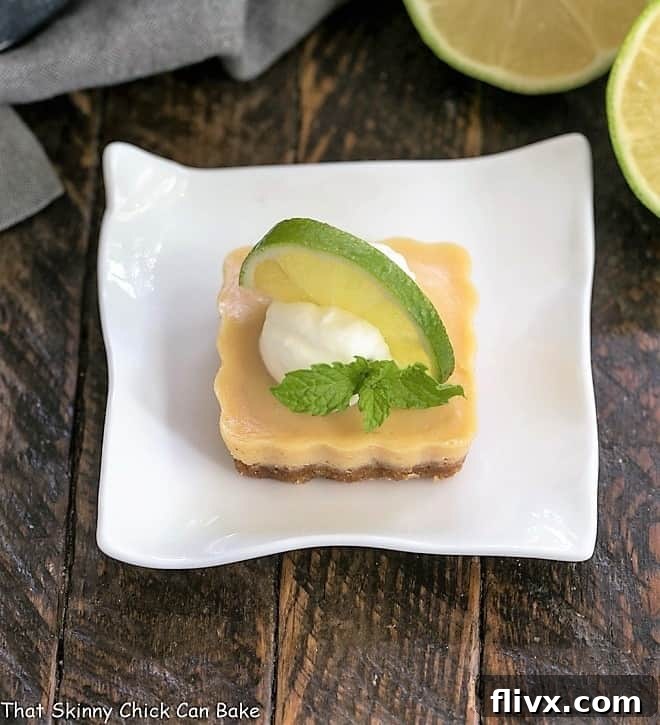 Key lime tartlet topped with cream and a half lime slice, a vibrant and enticing dessert.
