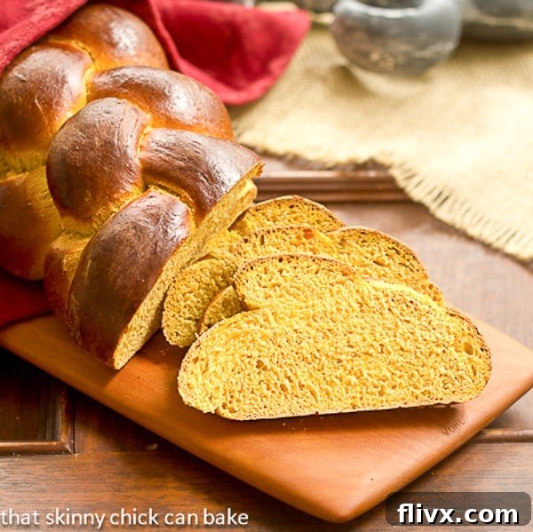 Perfectly baked Pumpkin Challah slices arranged on a wooden cutting board, showcasing its soft interior and beautiful color.