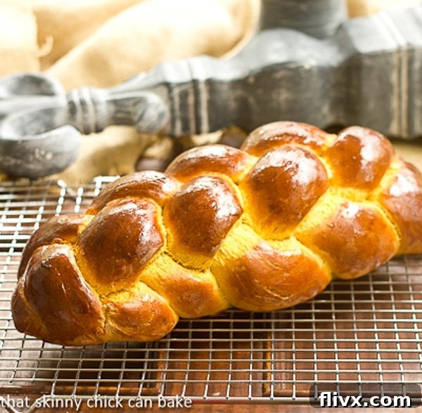A freshly baked Pumpkin Challah loaf cooling on a wire rack, showcasing its golden-brown crust and intricate braid.