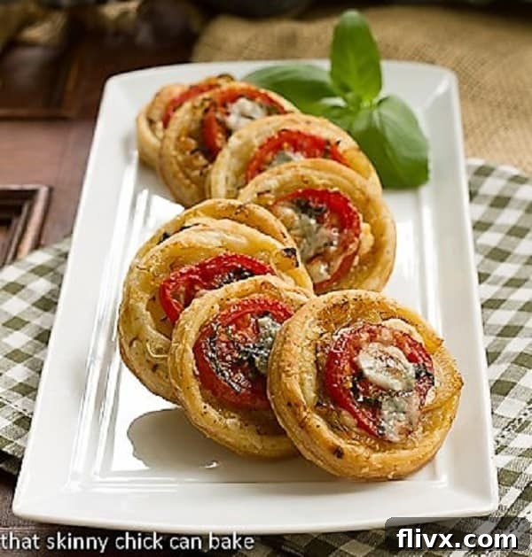Tomato and Boursin Tartlets on a white ceramic tray, garnished with fresh herbs.