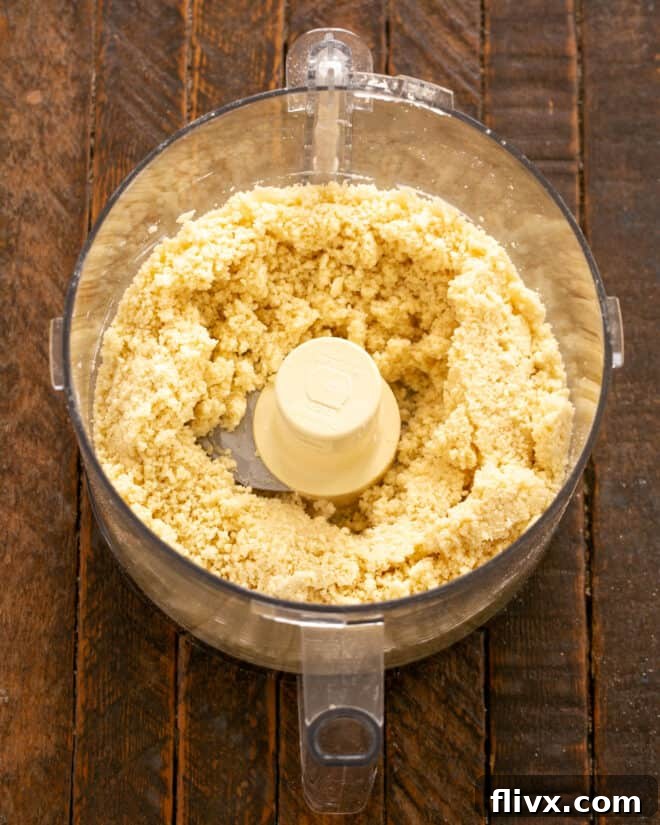Step 4: Ice water is slowly drizzled into the food processor while pulsing, just until the dough begins to come together.