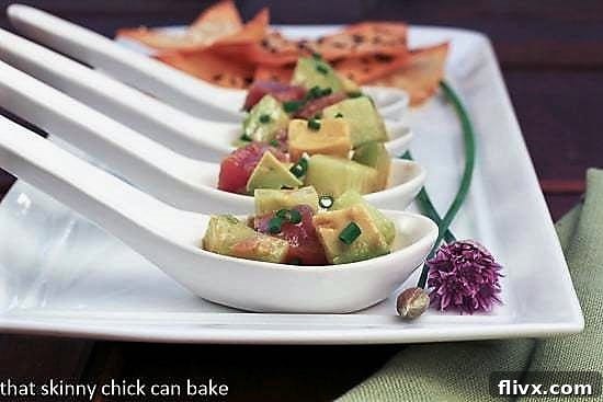 Elegant serving of Tuna tartare in delicate Asian spoons, presented on a pristine white tray, hinting at gourmet dining.