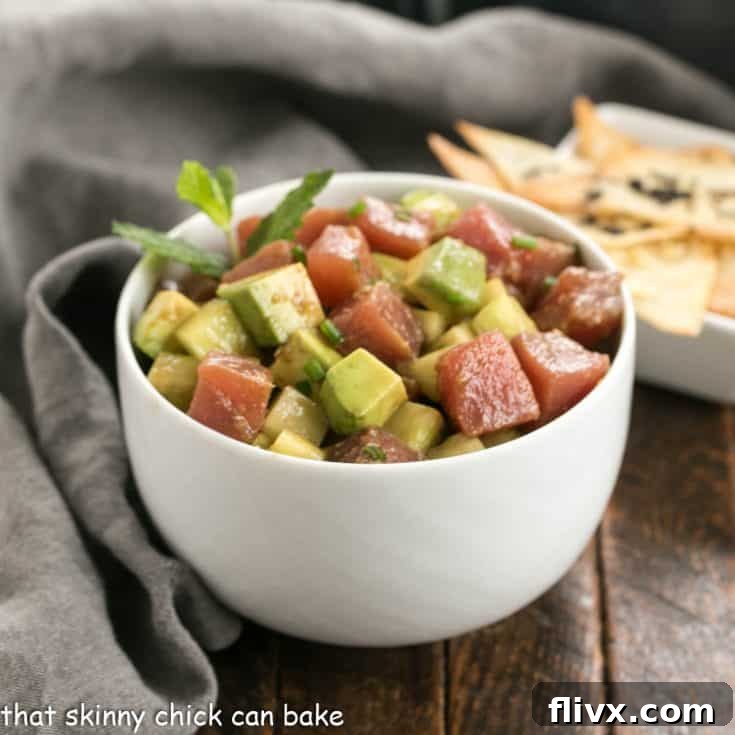 Tuna tartare with avocados in a white ceramic bowl in front of a small bowl of wonton chips