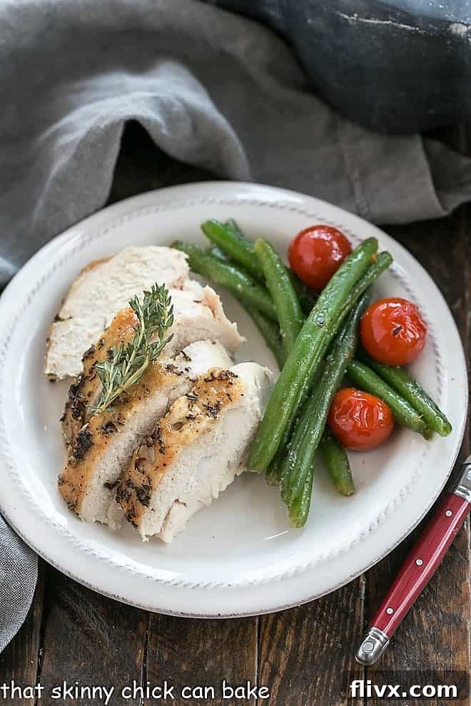 A perfectly golden-brown Oven Roasted Chicken, expertly carved and presented beautifully on a platter, garnished with fresh herbs and surrounded by vibrant roasted vegetables. The crispy skin promises a delightful texture.