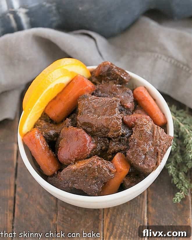 Overhead view of Slow Cooked Beef Stew with red wine in a white bowl, garnished with fresh thyme.