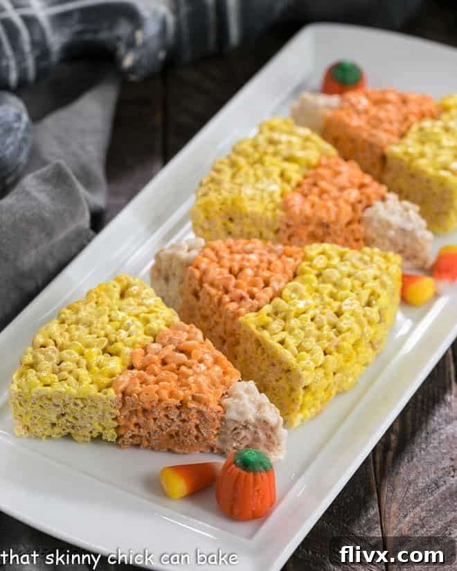 A large, rectangular white tray filled with an uncut slab of colorful Candy Corn Rice Krispie Treats, showcasing the layered design.