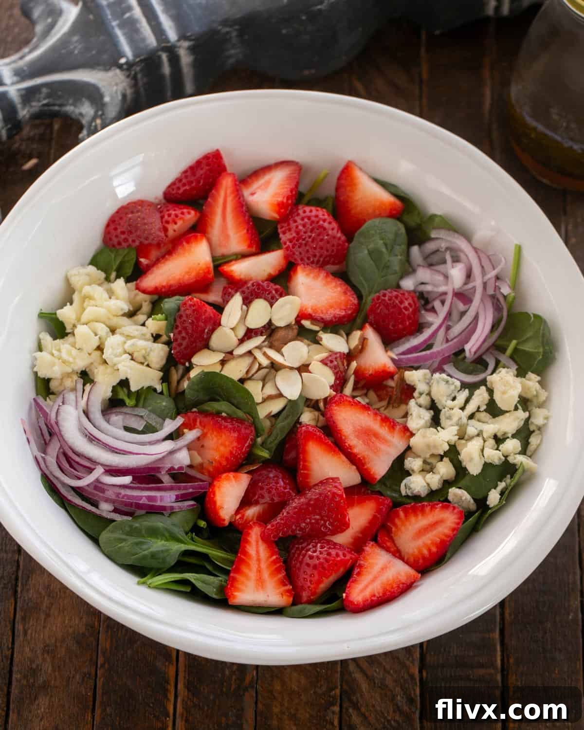 An overhead view of a vibrant Strawberry Spinach Salad with Blue Cheese, ready to be served in a large bowl.