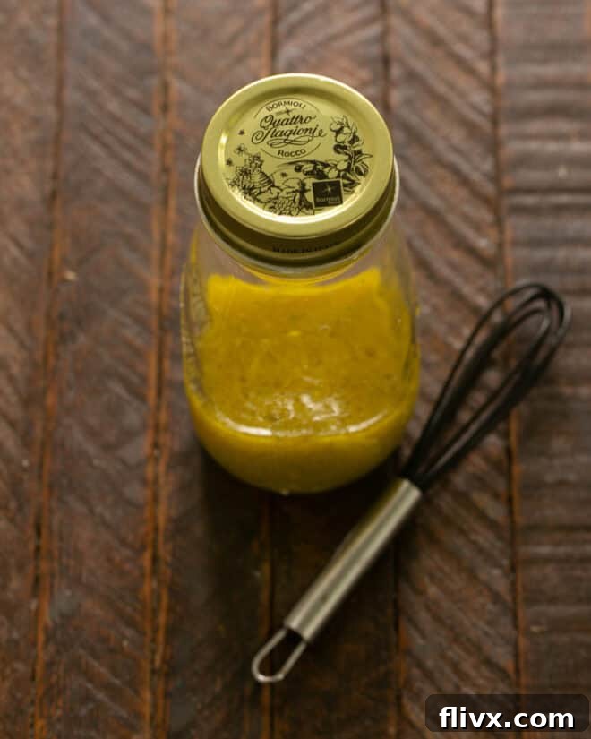Cobb Salad dressing, a smooth vinaigrette, in a glass jar, ready to be drizzled over the salad.