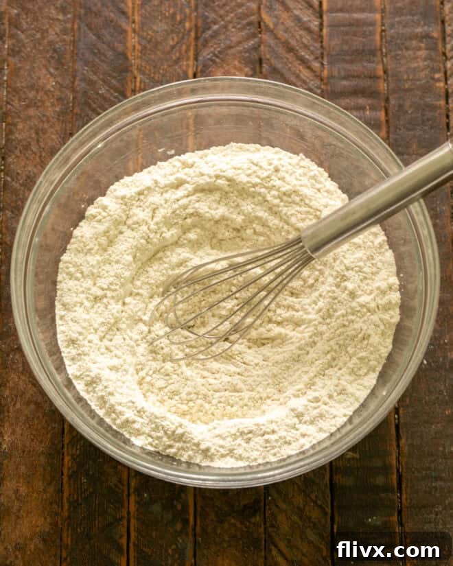 Dry ingredients including flour, baking powder, salt, sugar, and garlic powder being whisked together in a large mixing bowl.