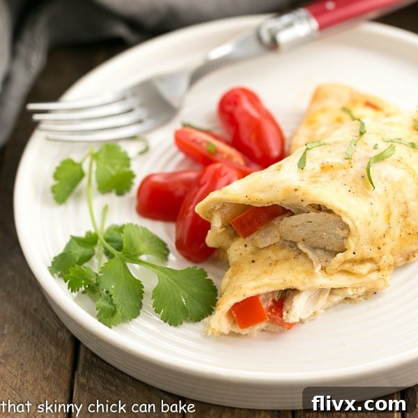 A single cheesy chicken enchilada on a white dinner plate, garnished with fresh cilantro and vibrant grape tomatoes.