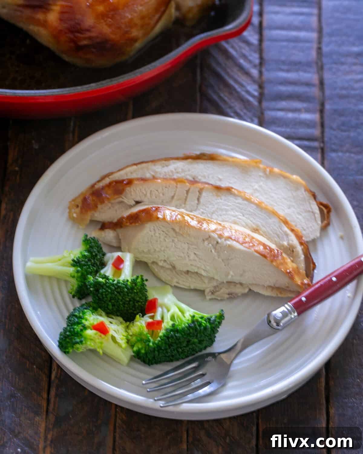 Perfectly roasted buttermilk chicken, expertly sliced and arranged on a plate, with the glistening roasting pan visible in the background.