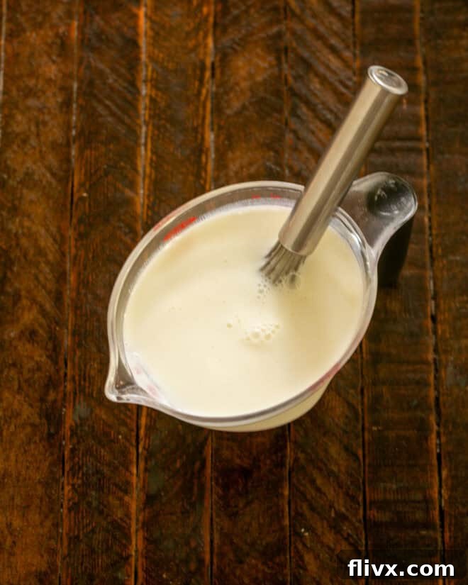 Buttermilk and salt in a measuring cup with a whisk.