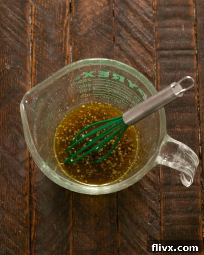 Italian vinaigrette in a Pyrex measuring cup with a small whisk.