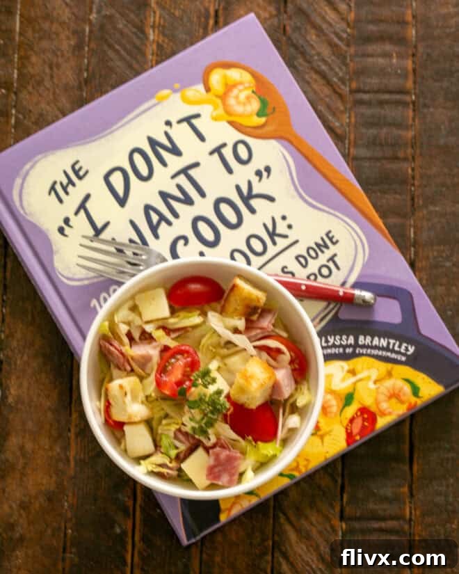 Serving of tossed sub salad resting on a cookbook.