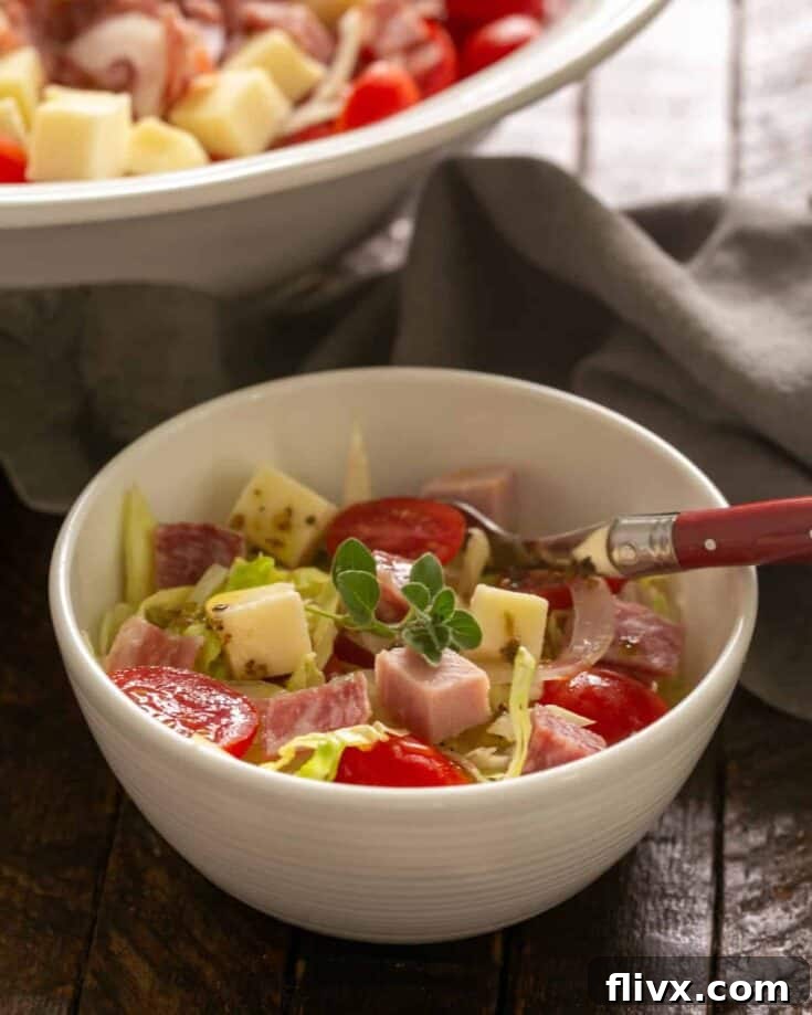 Italian chopped salad in a small bowl with a red handled spoon.