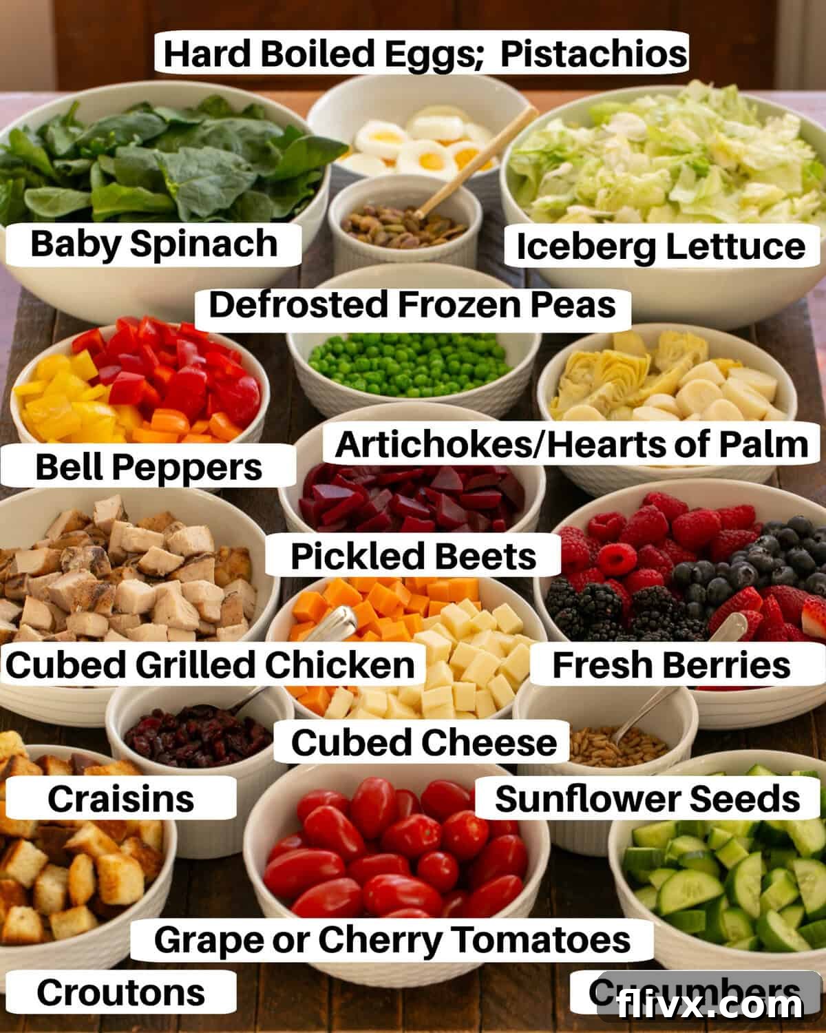 Assortment of fresh salad bar ingredients, including various vegetables, fruits, and add-ins, beautifully displayed in white serving bowls with labels.