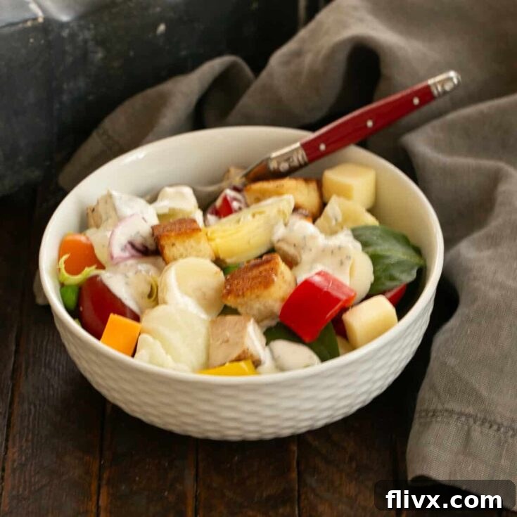 A vibrant salad in a white bowl with a red-handled fork, representing an easy salad bar setup for home entertaining.