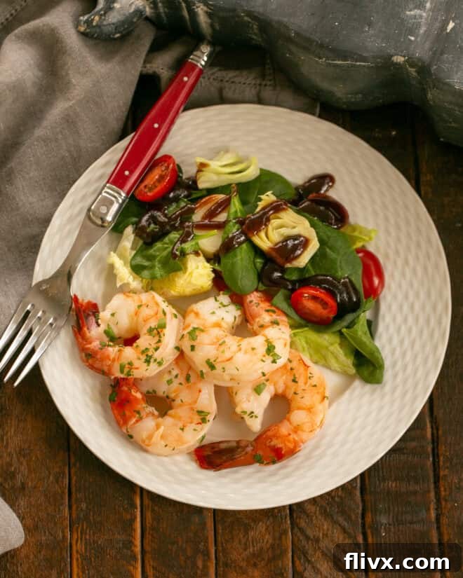 Shrimp scampi with salad and a fork on a white dinner plate.