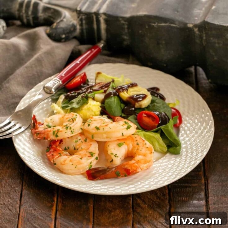 Shrimp scampi on a white dinner plate with salad and fork.
