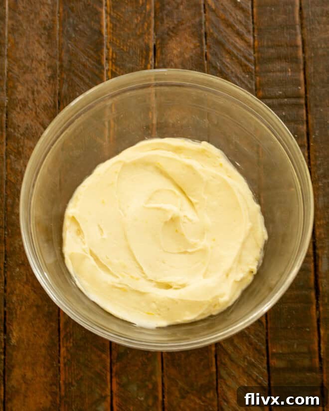 Cream cheese, lemon zest, lemon juice, vanilla, and fresh raspberries are mixed together in a bowl.