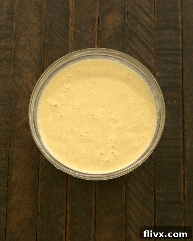 Sugar, remaining cream cheese, half and half, eggs, salt, lemon juice, and vanilla are whisked together to form a smooth custard.