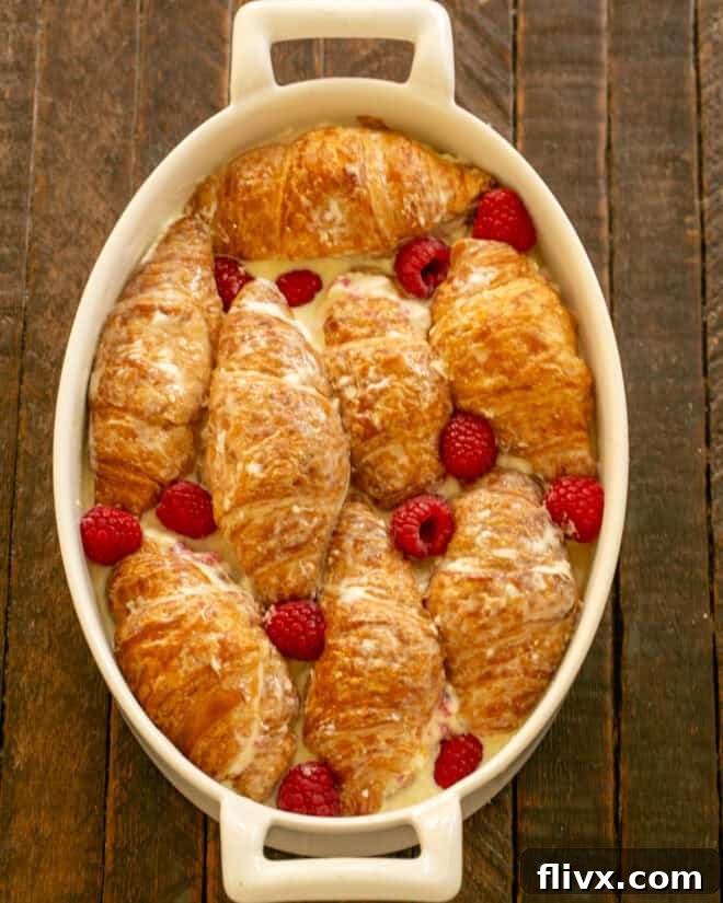 The tops of the croissants are placed back over the cream cheese filling, and the custard is poured over the entire casserole. The dish is then covered for chilling.