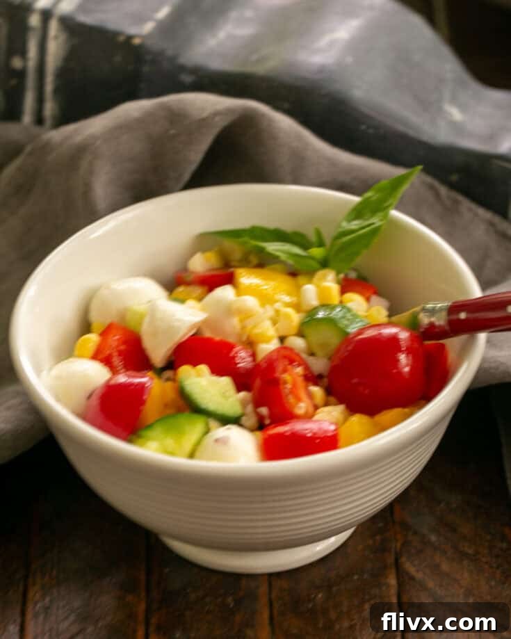 Serving of chopped summer salad in a white bowl with a red handled fork.