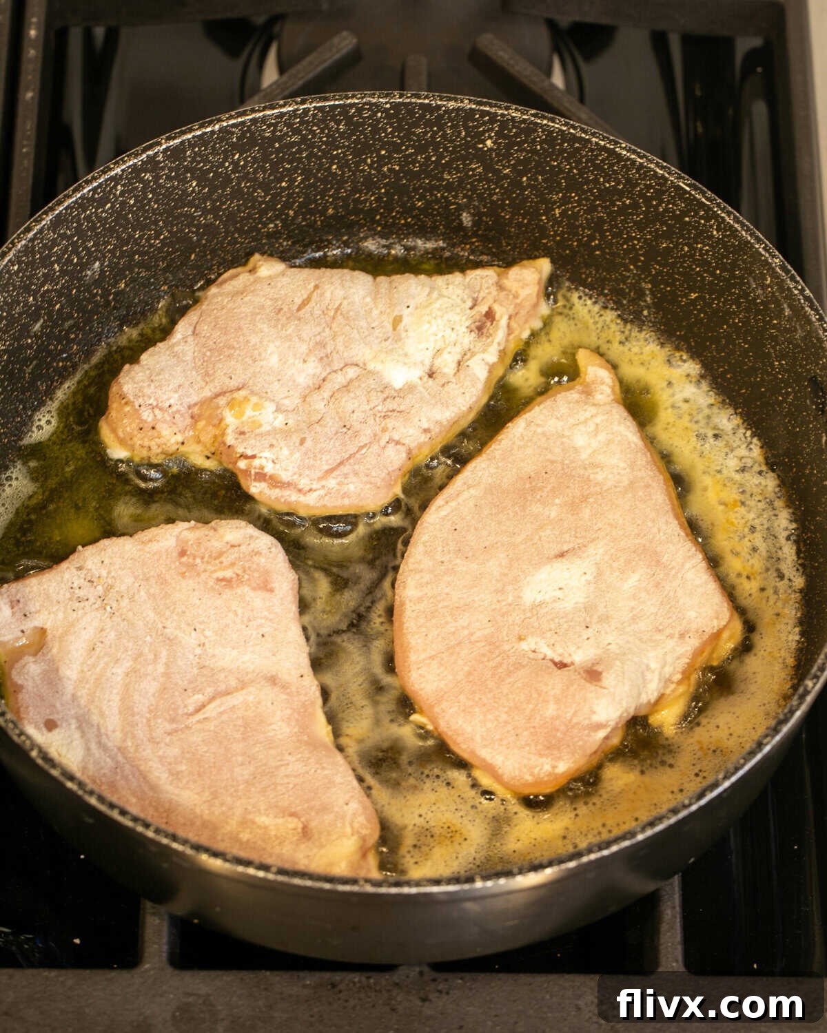 Chicken cutlets seasoned with salt, pepper, and flour, sizzling in a hot skillet with butter and olive oil.