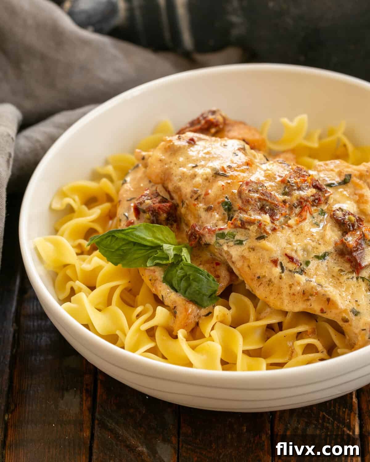 A creamy sauce simmering in a skillet with garlic, chicken broth, heavy cream, and sun-dried tomatoes, ready for the chicken to be added back.
