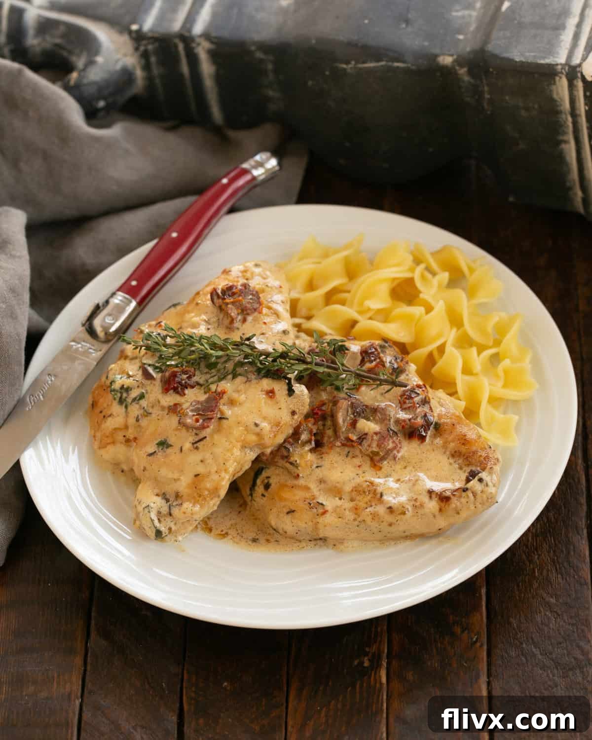 Marry Me Chicken served over a bed of buttered egg noodles, garnished with fresh basil.