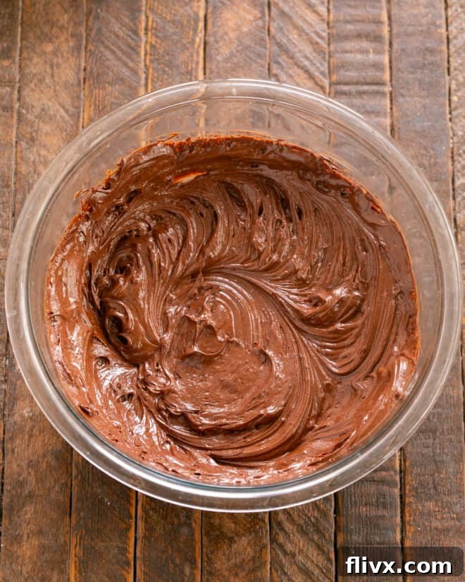 Melted chocolate and eggs being gently mixed together in a bowl, showing the mousse base.