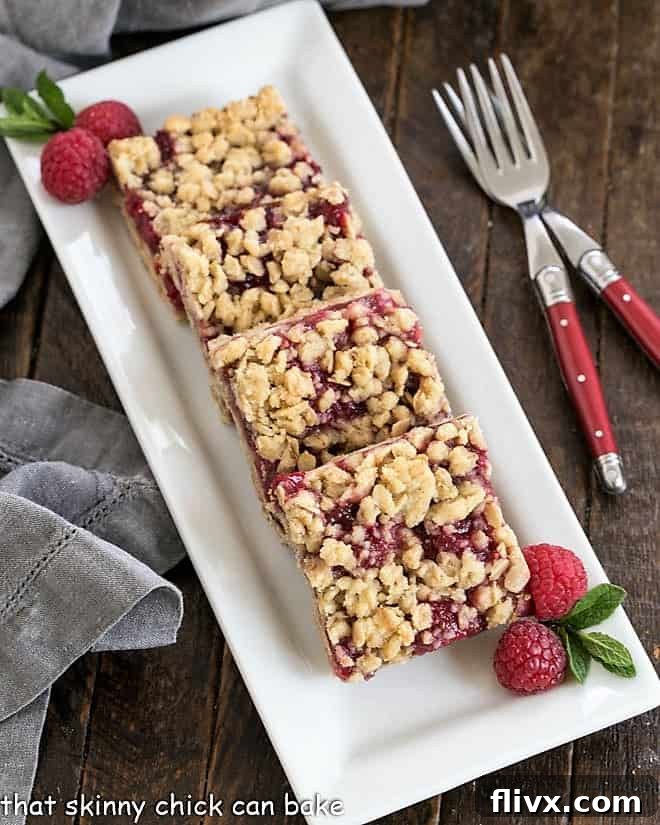 Overhead view of raspberry oatmeal bars on a white serving tray, highlighting the rich berry filling and golden streusel.