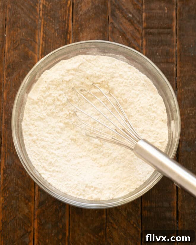 Dry ingredients (flour, baking soda, salt) whisked together in a mixing bowl, ready for combining.
