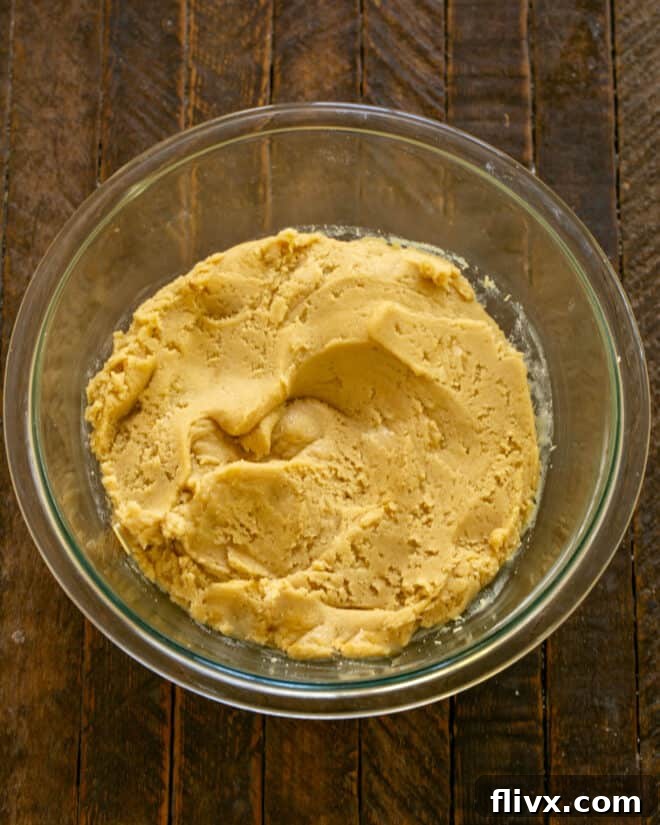 The whisked dry ingredients gradually added to the wet mixture, forming a cookie dough batter.