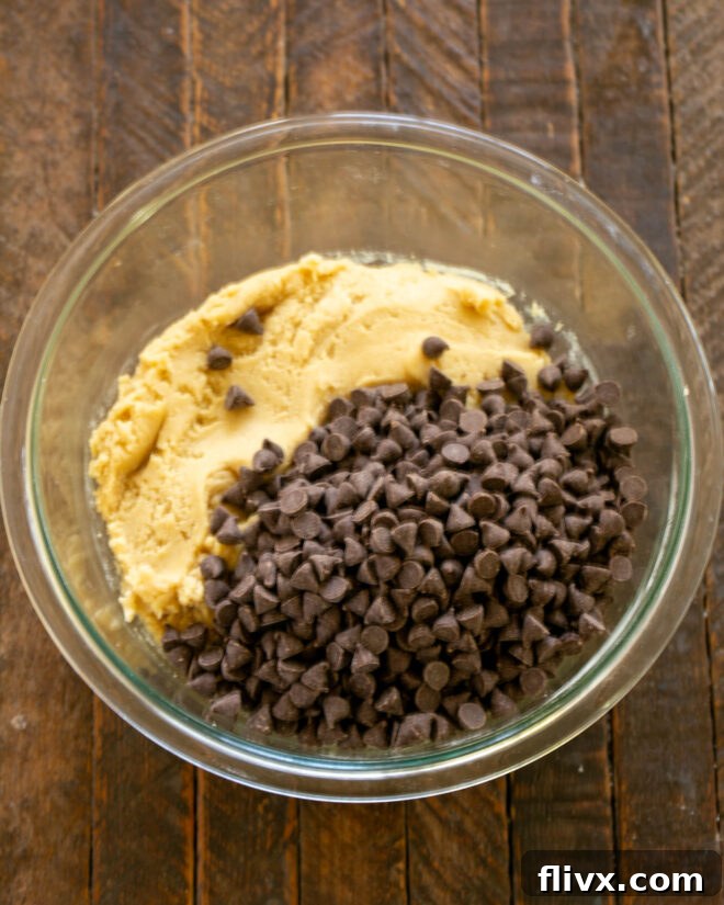 Chocolate chips being poured into the prepared cookie dough batter.