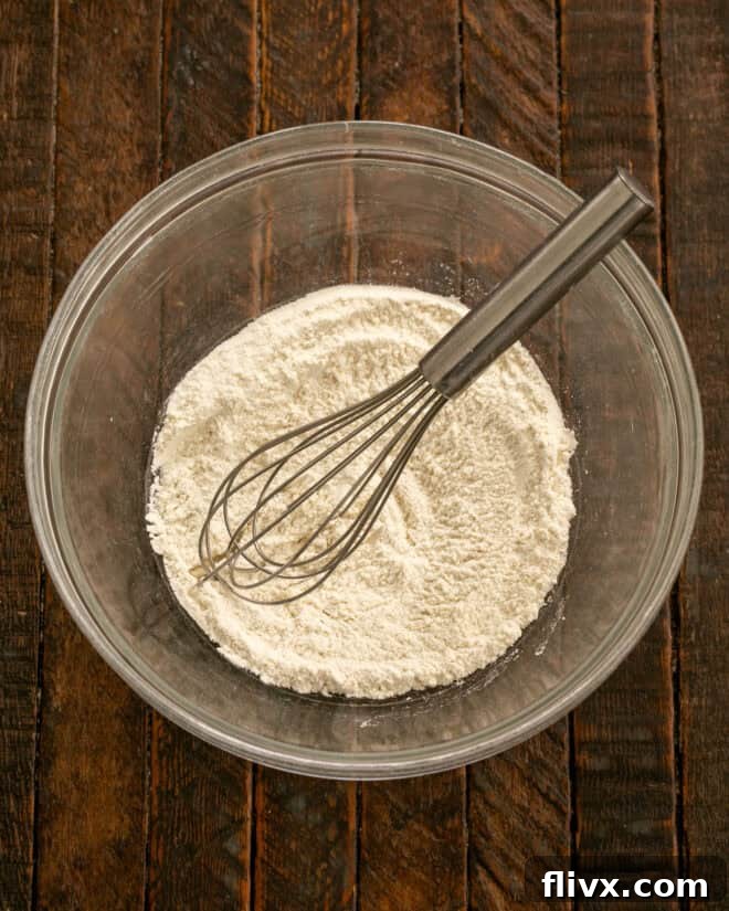 A medium-sized mixing bowl holds all the dry ingredients: flour, baking powder, and salt, perfectly combined and ready for the next step in making double chocolate cookies.