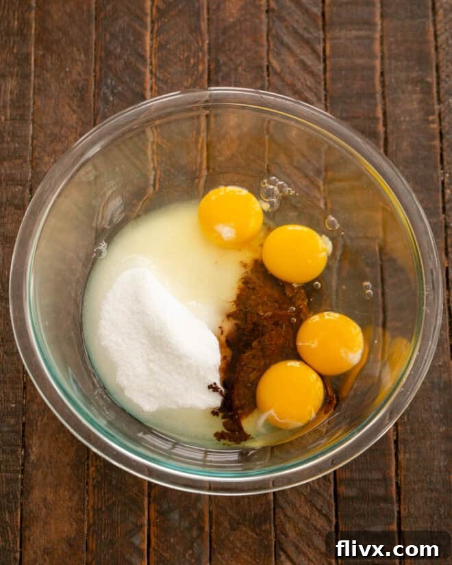 In a separate mixing bowl, eggs, sugar, instant coffee, and vanilla extract are combined, ready to be whisked into a light and airy mixture for the double chocolate cookies.