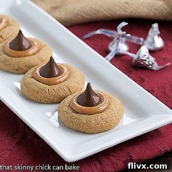Irresistible Caramel Biscoff Blossom Cookies neatly arranged on a white ceramic tray, showcasing their golden-brown edges, caramel centers, and chocolate kisses.
