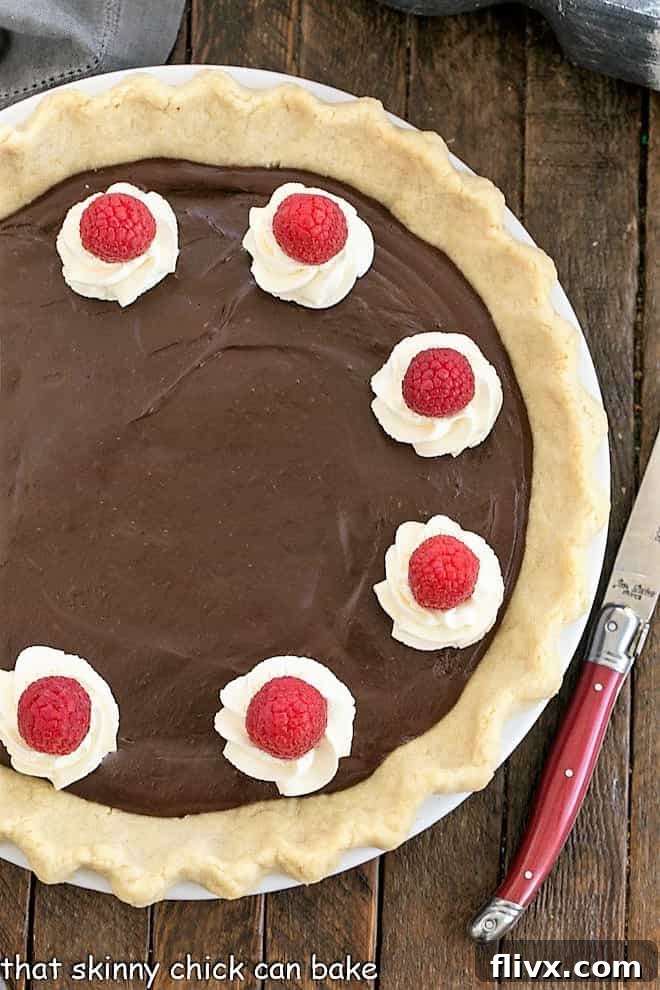 Overhead view of a chocolate cream pie with a red handled knife