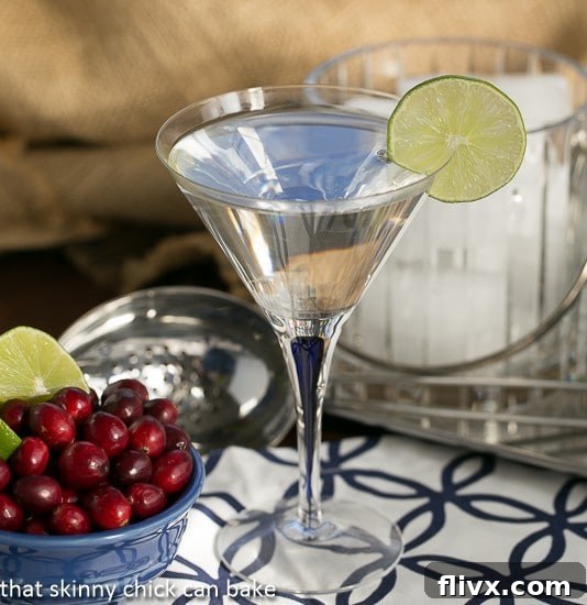 White Cosmopolitans garnished with a slice of lime and fresh cranberries.