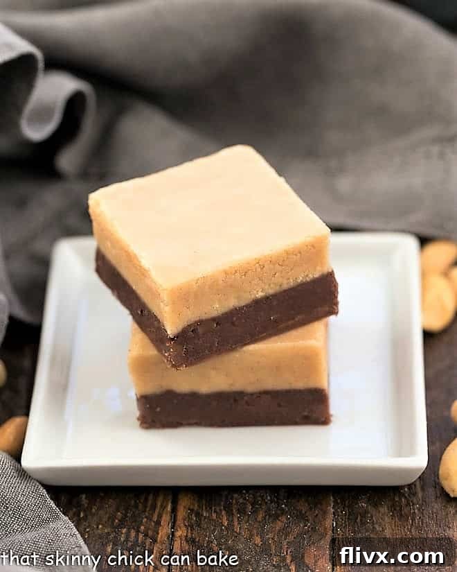 Irresistibly Smooth Peanut Butter Fudge - A delight on its own, and a perfect layer in our famous chocolate peanut butter fudge. Two perfectly cut squares of creamy peanut butter fudge resting on a minimalist square white plate, highlighting its smooth texture.