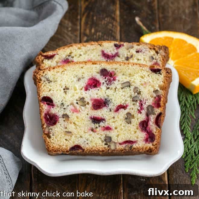 Two slices of cranberry orange bread on a square white plate, ready to be served.