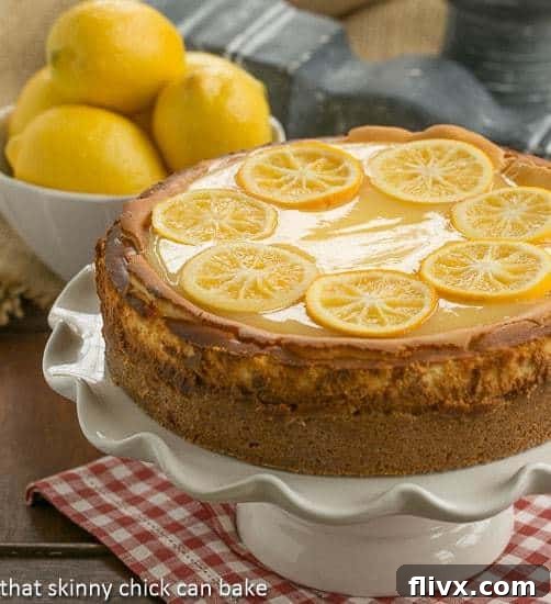 Lemon Bar Cheesecake on a white cake stand, elegantly garnished with lemon slices.