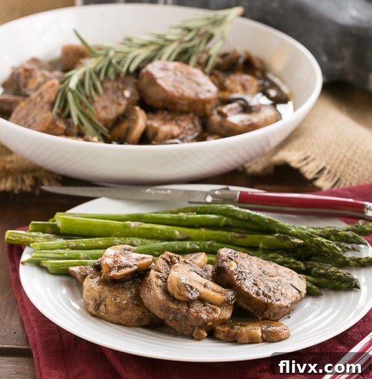 Pork Tenderloin with Maple Balsamic Glaze on a white plate with asparagus spears and a red handle knife