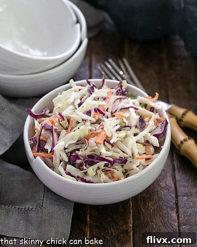 The Best Coleslaw Recipe - Perfect slaw for picnics and gatherings KFC coleslaw recipe in a white bowl with two spare bowls in the background, ready for serving.