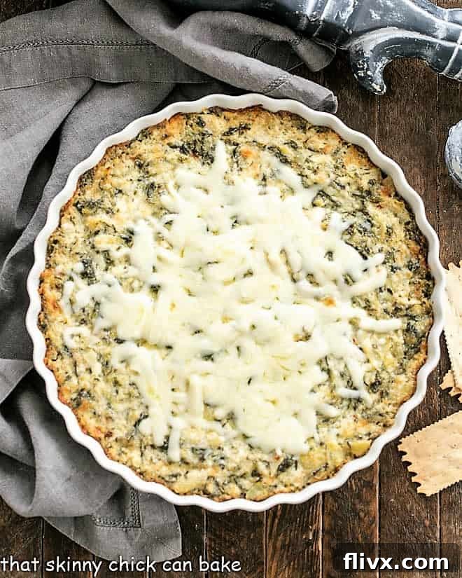 Overhead view of spinach dip in a round white dish, perfectly baked with a golden, bubbly top.
