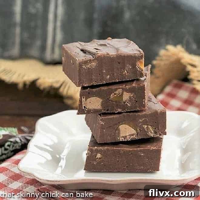 Three squares of Milky Way Fudge stacked on a small white dessert plate with a blurred background.