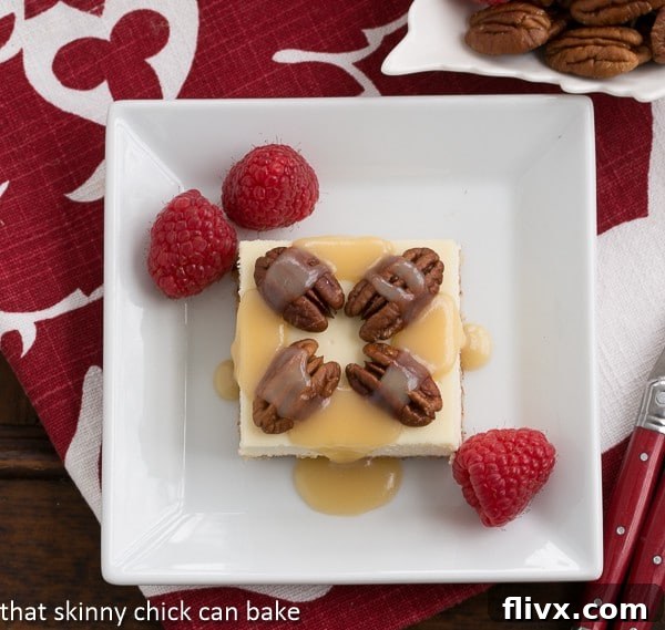 Caramel Pecan Cheesecake Bars on a square white plate on a red and white napkin.
